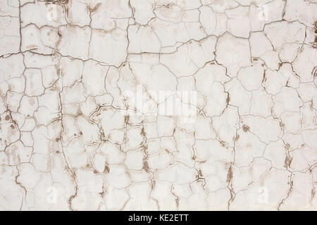 Grungy et mur de béton peint en blanc sale surface couverte dans les fissures Banque D'Images