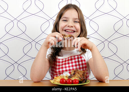 Happy little girl eating chicken wings Banque D'Images