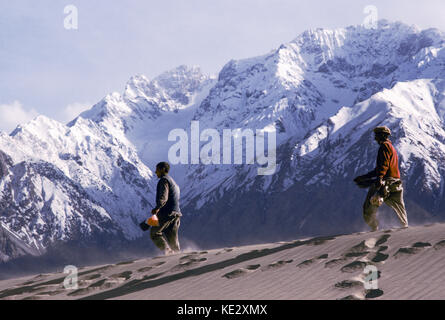 Les hommes de marcher à travers les dunes de sable près de Skardu, la haute vallée de l'Indus, au Cachemire, au Pakistan, en 1990. Banque D'Images