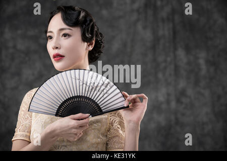 Portrait of young smiling woman in oriental style rétro clothes posing avec ventilateur Banque D'Images