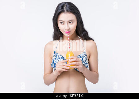 Slim young smiling woman in bikini drinking orange juice Banque D'Images