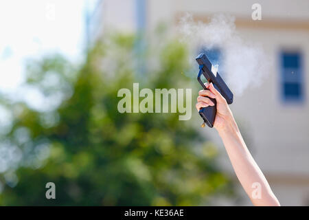 Main tenant le pistolet de démarrage dans le jardin de l'école Banque D'Images