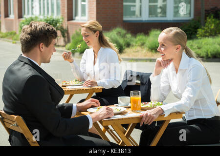 Les jeunes hommes et femmes d'affaires heureux de manger de la nourriture dans le restaurant Banque D'Images