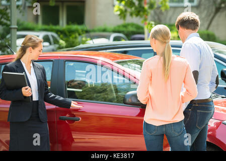 Certains jeunes femmes montrant les nouveaux Concessionnaires voiture rouge pour couple Banque D'Images