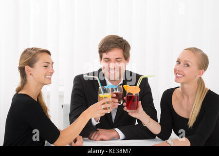 Group Of Smiling Young Friends Drinking Cocktails In Restaurant Banque D'Images