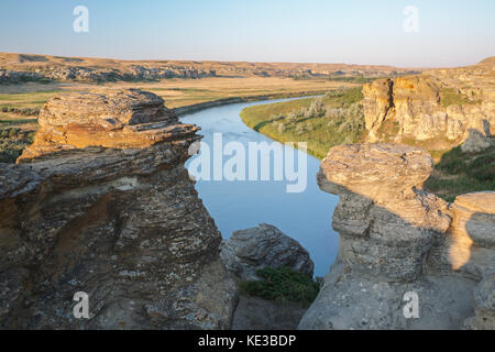 Des formations rocheuses, des cheminées et la rivière Milk au lever du soleil au parc provincial Writing-on-Stone, Alberta, Canada. Banque D'Images