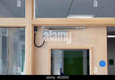 Gros plan d'un ferme-porte de feu magnétique à commande électronique sur les portes intérieures dans un bâtiment d'université du Royaume-Uni. Banque D'Images