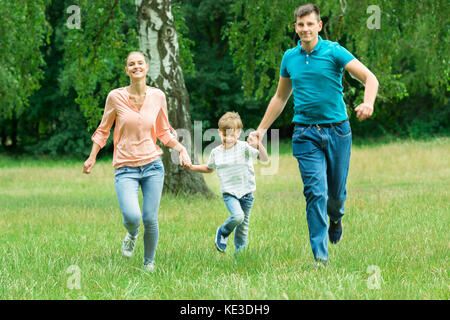 Famille heureuse maintenant chaque autres mains lors de l'exécution dans le parc Banque D'Images