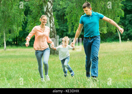 Famille heureuse maintenant chaque autres mains lors de l'exécution dans le parc Banque D'Images