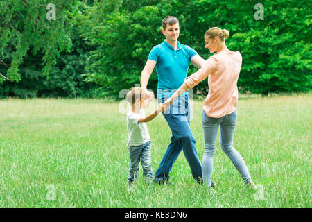 Heureux jeune Famille se tenant les mains tout en jouant dans le parc Banque D'Images