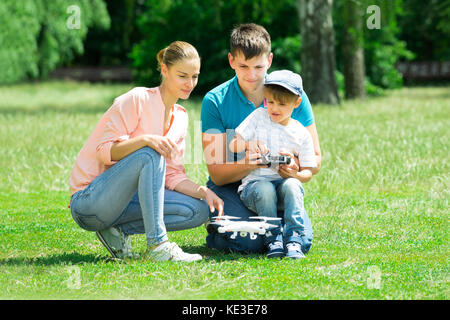 Un garçon d'utiliser le drone par commande à distance avec ses parents dans le parc Banque D'Images