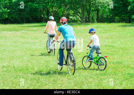 Vue arrière d'une famille équestre Location sur l'herbe verte dans le parc Banque D'Images