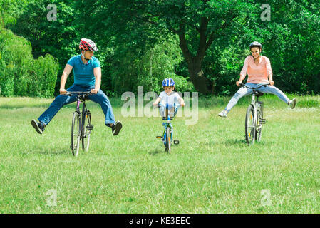 Happy Boy bénéficiant d'équitation à bicyclette dans le parc avec ses parents Banque D'Images