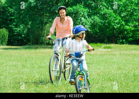 Mère et Fils profiter de la promenade en vélo dans le parc Banque D'Images