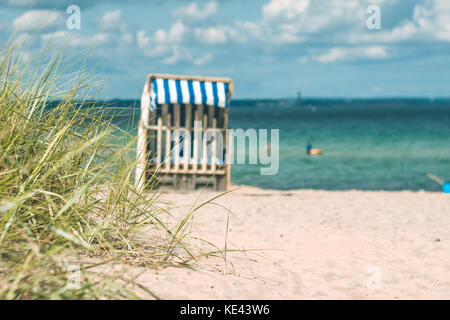 Dune avec un peu d'herbe et de chaises de plage en bois traditionnel sur la plage de sable. L'Allemagne du nord, sur la côte de la mer Baltique Banque D'Images