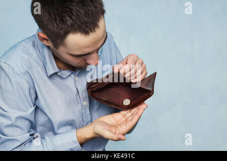 Un jeune homme de race blanche dans les jeans de prendre quelques pièces de sa poche. le gars compte l'argent. pauvre étudiant. Banque D'Images