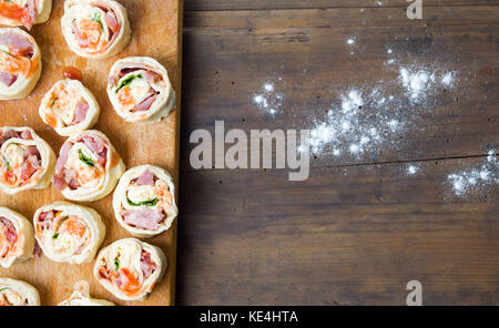 Rouleaux de pizza brut sur une planche à découper en bois Banque D'Images