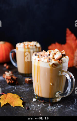 Pumpkin spice latte de crème fouettée, de la sauce au caramel et chocolat sur fond noir. vertical, l'espace pour copier du texte. automne confort alimentaire Banque D'Images