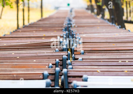 Deux lignes ou le blanc et marron des bancs de parc stockées dans le coin d'un parc public pour un hiver froid saison. vue en perspective. Banque D'Images