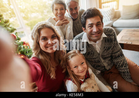 Extended family en tenant à la maison selfies dans le salon. Femme avec sa famille taking self portrait, la veille de Noël. Banque D'Images