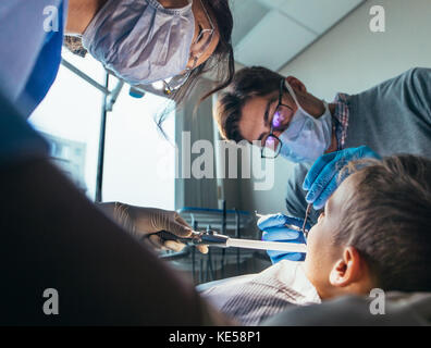 Infirmière dentiste pédiatrique avec le traitement de dents d'un petit garçon d'un patient à la clinique dentaire. Petit garçon obtenir un traitement dentaire. Banque D'Images