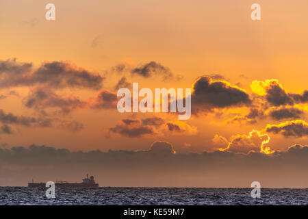 Un grand cargo chefs dans la mer du Nord comme le soleil se lève à l'horizon. Banque D'Images