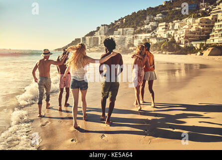 Des jeunes amis en couple marchent sur la plage ensoleillée d'été Banque D'Images