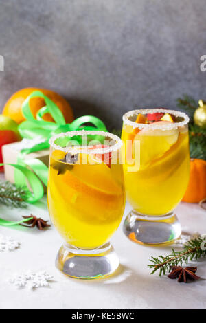 Cocktail de noël fait maison vin blanc épicé avec des bâtons de cannelle, d'anis étoile et des morceaux de fruits, servi dans deux tasses sur une pierre ou gris ardoise. Banque D'Images