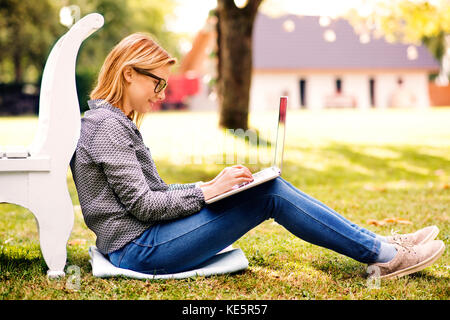 Jeune femme avec un ordinateur portable qui étudient à l'extérieur. Banque D'Images