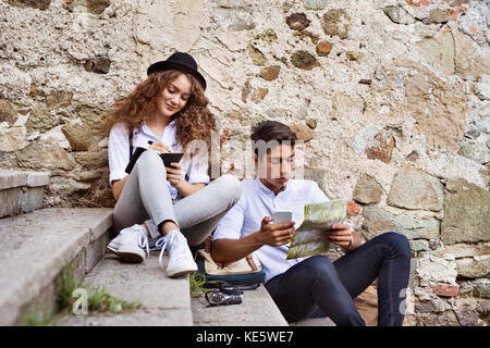 Deux belles jeunes touristes avec smartphone, la carte et l'appareil photo dans la vieille ville. Les adolescents assis dans les escaliers, d'écriture. Banque D'Images