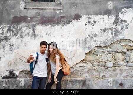 Deux belles jeunes touristes avec le smartphone et l'appareil photo dans la vieille ville, avec le smartphone selfies. Banque D'Images