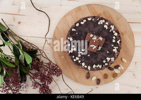 Un beau plat de gâteau snickers végétalien premières avec des fleurs à côté dans une petite pâtisserie. Banque D'Images