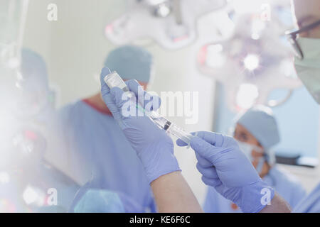 Anesthésiste masculin avec seringue préparant le médicament d'anesthésie en salle d'opération Banque D'Images