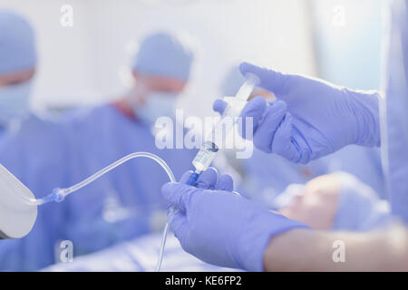 Fermez l'anesthésiste avec la seringue injectant le médicament d'anesthésie dans IV égouttement dans la salle d'opération Banque D'Images