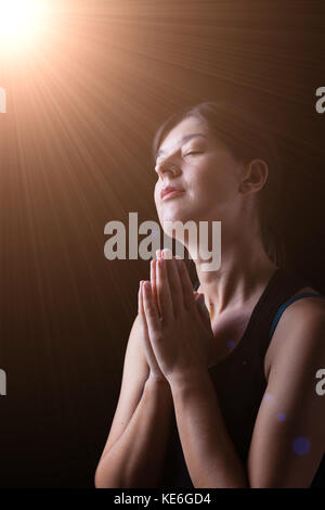 Femme fidèles priant et souriant de bonheur, bonheur et paix, sous une lumière céleste ou divine sentiment inspiré avec la présence de Dieu Banque D'Images