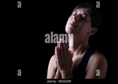 Femme en prière fidèle et le sentiment de la présence ou de l'être touché par Dieu. mains jointes en prière, la tête et les yeux fermés Banque D'Images