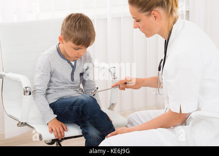 Heureux femme médecin contrôle réflexe du genou sur un patient dans un centre pour enfants Banque D'Images