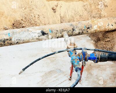 Fouille. vieux 500mm boire de l'eau tuyau avec 150mm bras de virage avec robinets-vannes, raccords tubes corrodés rejoindre. tuyauterie avant réparation. asphal Banque D'Images