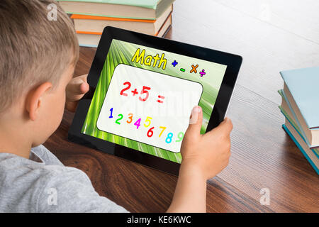 Gros plan de Boy Solving Math Problem sur la tablette numérique en classe Banque D'Images