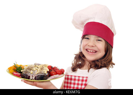 Happy little girl cook avec de la truite et de la salade sur l'assiette Banque D'Images