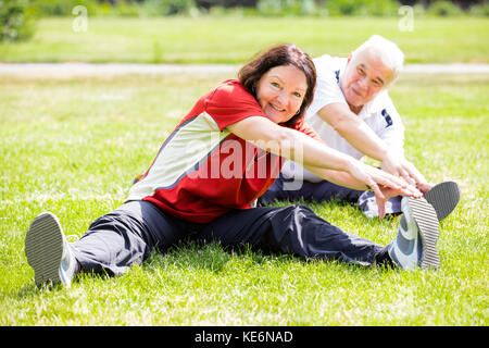Smiling senior couple doing fitness exercise in park Banque D'Images