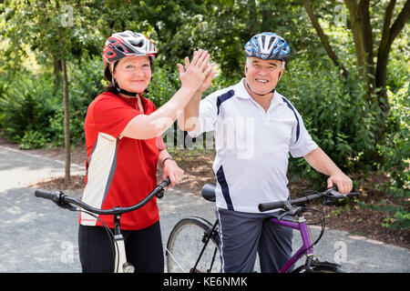 Couple avec leurs bicyclettes offrant un rapport de 5 pour chaque autre Banque D'Images