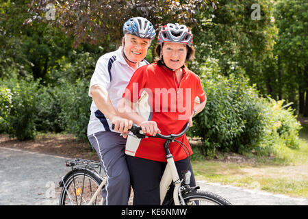 Portrait Of Happy Senior Couple With Bicycle In Park Banque D'Images