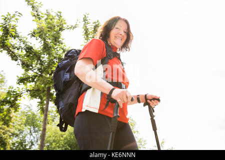 Portrait Of A Happy Senior Female Hiker avec pôle Randonnée Banque D'Images