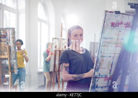 Portrait femme peintre souriante avec tatouages peinture en classe d'art studio Banque D'Images