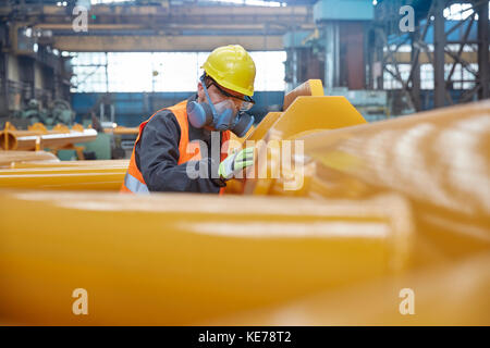 Ouvrier de l'acier portant un masque facial de protection, examinant l'équipement dans l'usine d'acier Banque D'Images