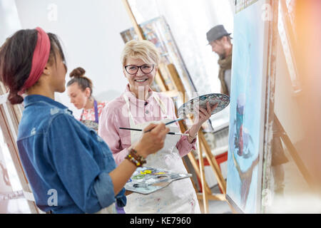 Artistes féminins souriants avec pinceaux et palettes de peinture dans l'art classe studio Banque D'Images