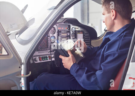 Homme ingénieur vérifiant les diagnostics avec une tablette numérique dans le cockpit d'avion Banque D'Images