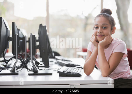 Portrait confiante jeune fille étudiant à la recherche à l'ordinateur dans la bibliothèque Banque D'Images