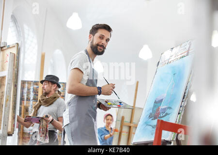 Portrait confiante homme artiste peinture avec palette en classe d'art studio Banque D'Images